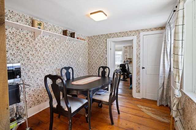 dining room with wallpapered walls, baseboard heating, and hardwood / wood-style flooring