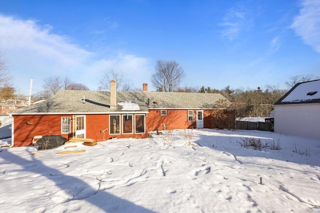 snow covered house featuring a chimney