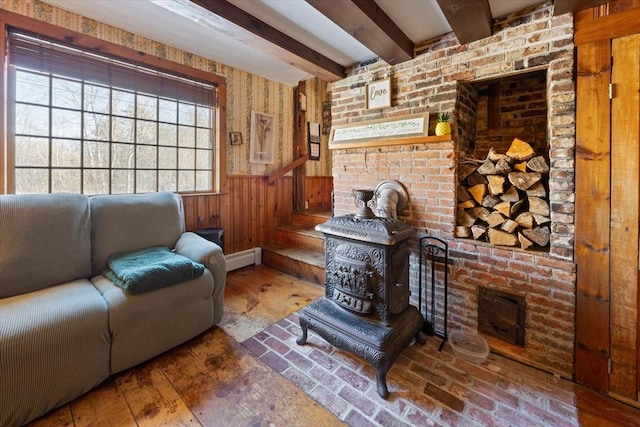 living area with brick floor, beam ceiling, a baseboard radiator, wainscoting, and wooden walls