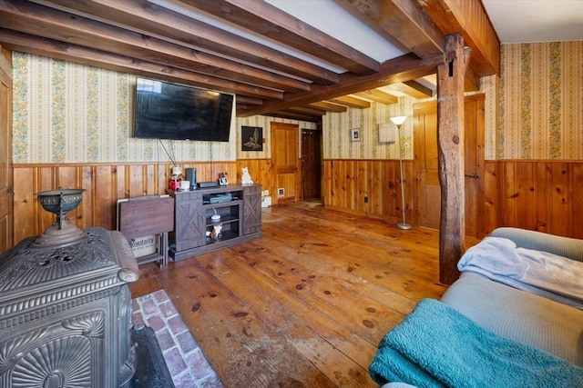 living area featuring a wainscoted wall, wallpapered walls, and beamed ceiling