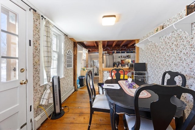 dining space with a baseboard heating unit, hardwood / wood-style floors, and wallpapered walls