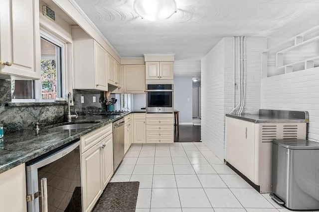 kitchen featuring appliances with stainless steel finishes, a sink, decorative backsplash, light tile patterned floors, and wine cooler