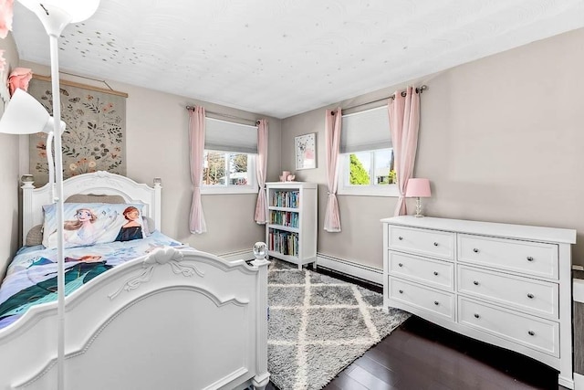 bedroom featuring dark wood-style flooring and a baseboard heating unit