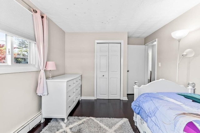 bedroom with dark wood-style flooring, baseboards, a closet, and a baseboard radiator