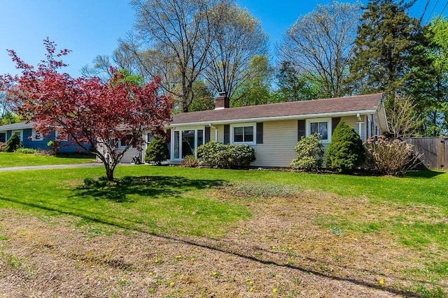 view of front of home with fence, a chimney, and a front lawn
