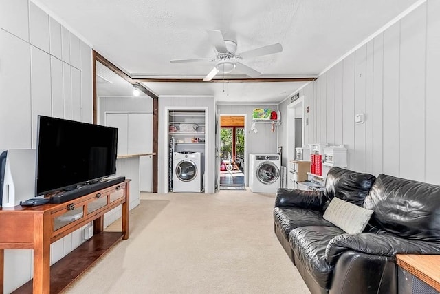 living area featuring a decorative wall, a ceiling fan, washer / clothes dryer, and light colored carpet