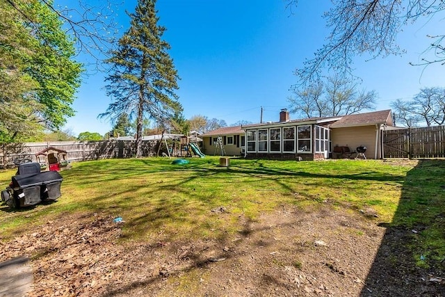 view of yard with a sunroom, a fenced backyard, a playground, and a gate