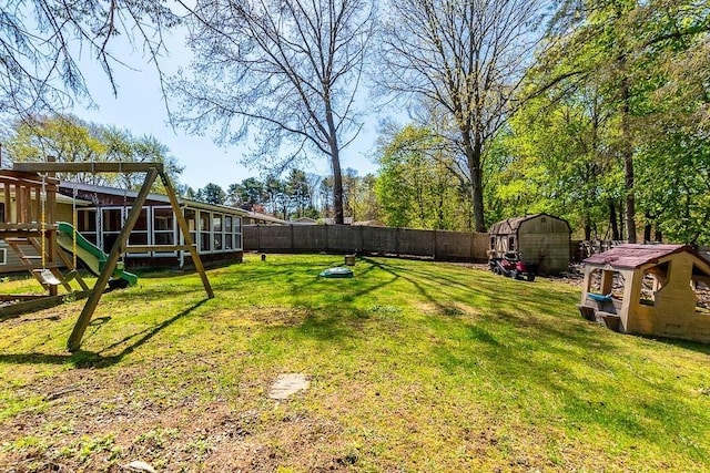 view of yard featuring a fenced backyard, a storage unit, an outbuilding, and a sunroom