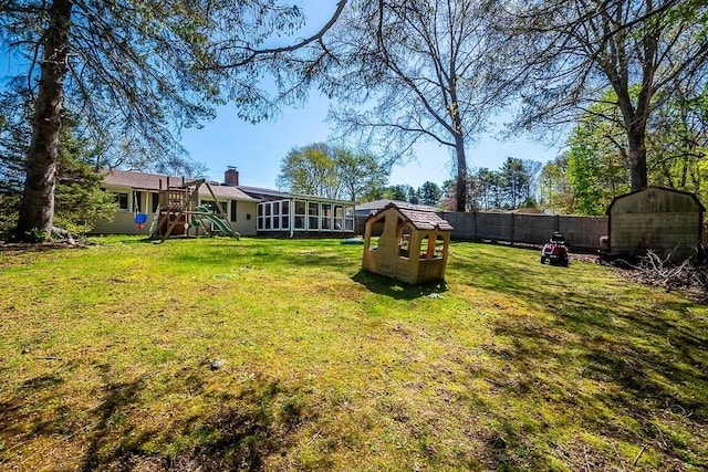 view of yard with a playground, fence, an outbuilding, and a storage shed