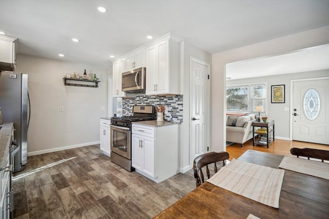 kitchen featuring recessed lighting, stainless steel appliances, dark wood-style flooring, white cabinetry, and backsplash