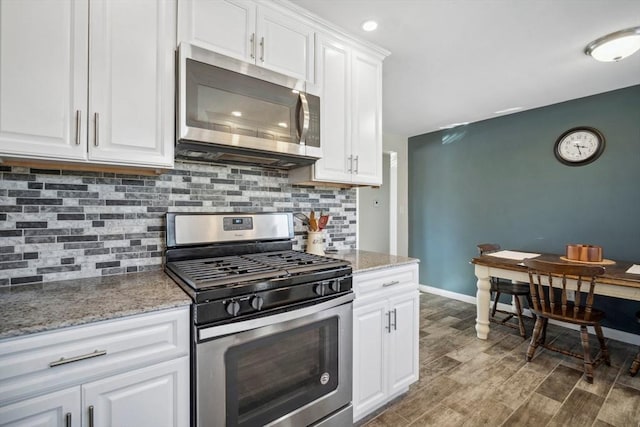 kitchen featuring tasteful backsplash, baseboards, wood finished floors, stainless steel appliances, and white cabinetry