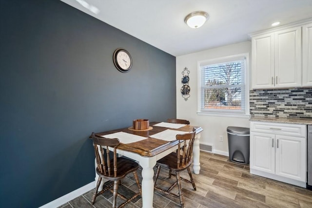 dining room featuring visible vents, baseboards, and wood finished floors