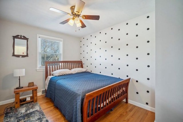 bedroom featuring visible vents, a ceiling fan, light wood-style flooring, and baseboards