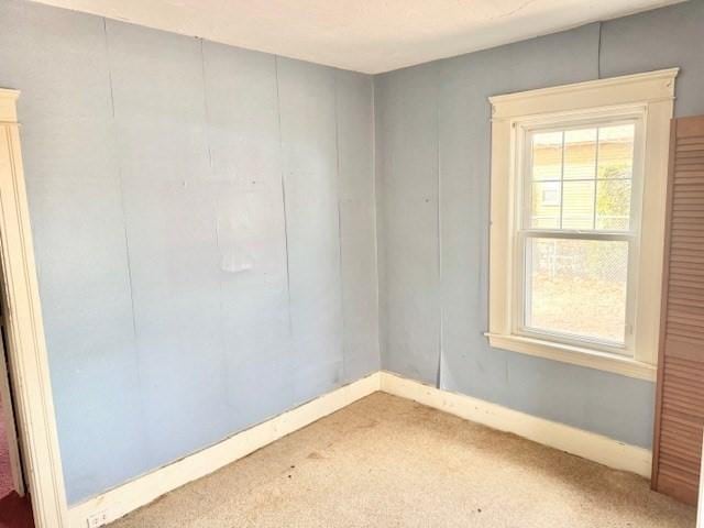 carpeted spare room featuring baseboards