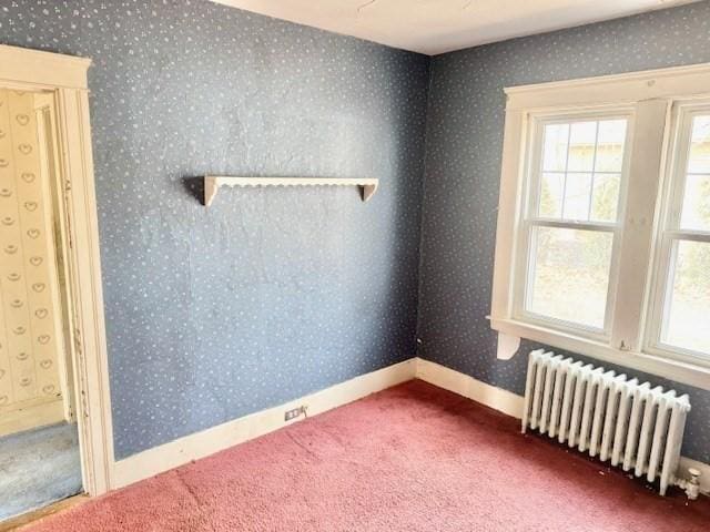 carpeted spare room with wallpapered walls, radiator heating unit, and baseboards