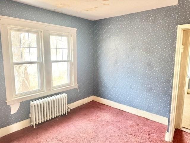 empty room with baseboards, wallpapered walls, carpet flooring, and radiator