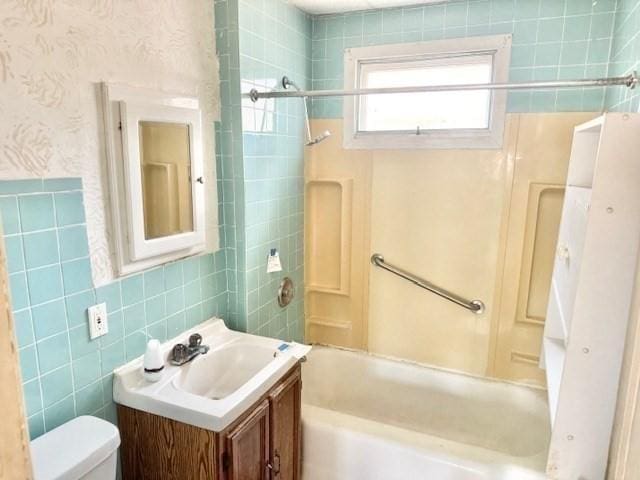 bathroom with toilet, vanity, tile walls, and shower / bathtub combination