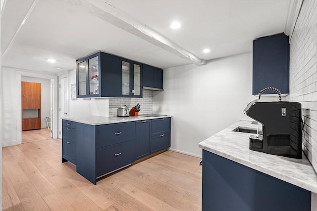 kitchen featuring tasteful backsplash, blue cabinets, black electric stovetop, and light hardwood / wood-style flooring