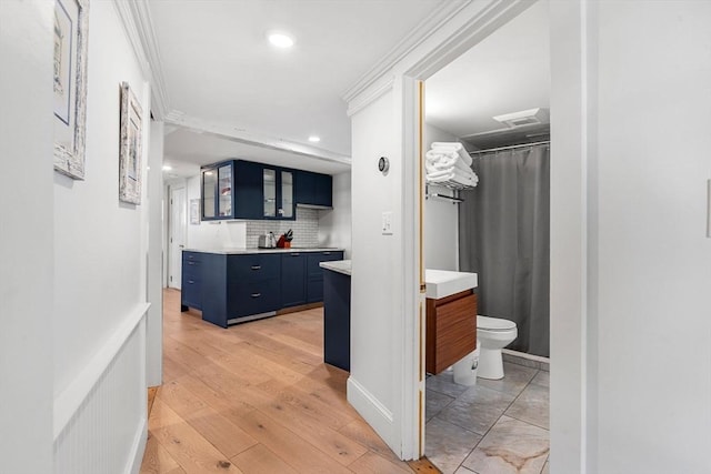 bathroom featuring crown molding, vanity, toilet, and decorative backsplash