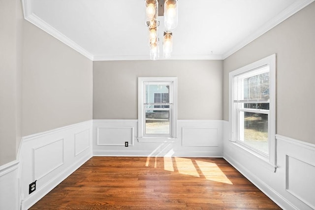 unfurnished dining area with dark wood finished floors, a notable chandelier, wainscoting, and crown molding