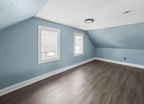 additional living space with lofted ceiling, baseboards, and dark wood-style flooring