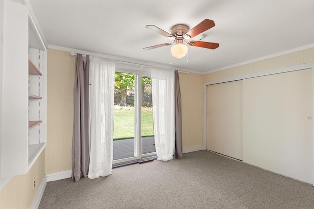 unfurnished bedroom with a closet, ornamental molding, carpet, ceiling fan, and access to exterior