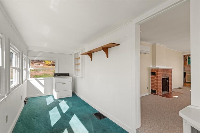 interior space featuring washer / clothes dryer, a wall mounted air conditioner, ornamental molding, carpet flooring, and a fireplace