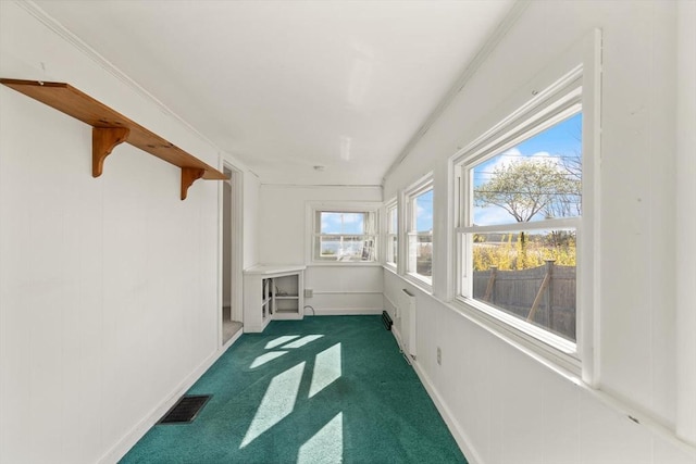 unfurnished sunroom with baseboards, visible vents, and carpet floors