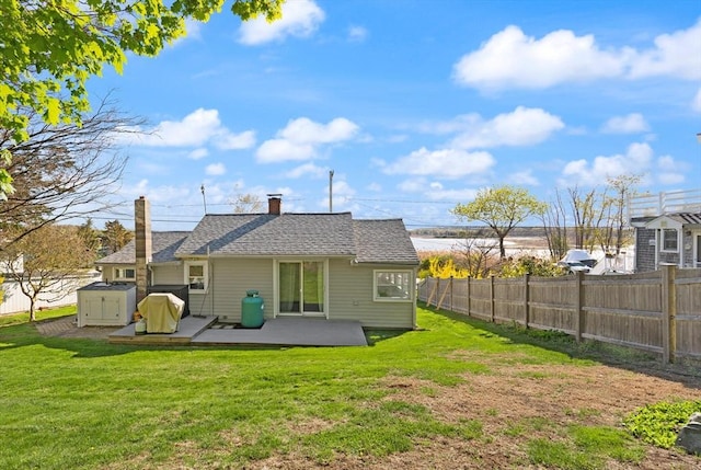 back of property featuring a lawn, a chimney, a patio area, and fence