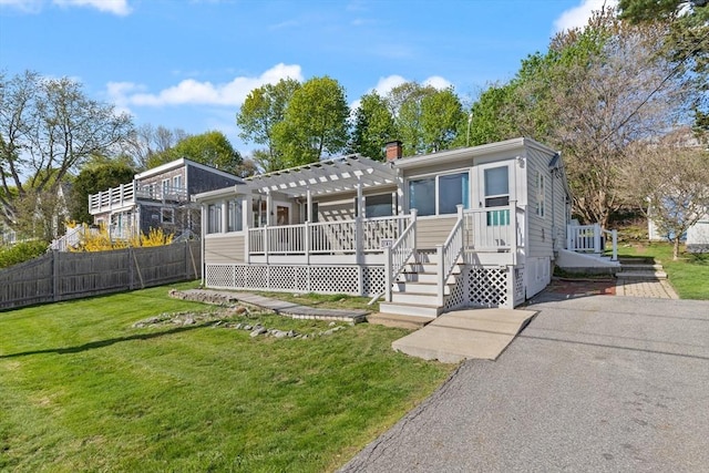 view of front of home featuring a pergola, fence, and a front lawn