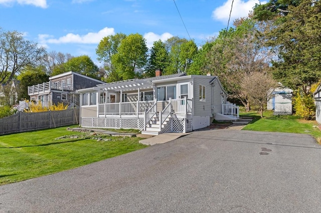 view of front of property featuring a pergola, fence, a front lawn, and a chimney