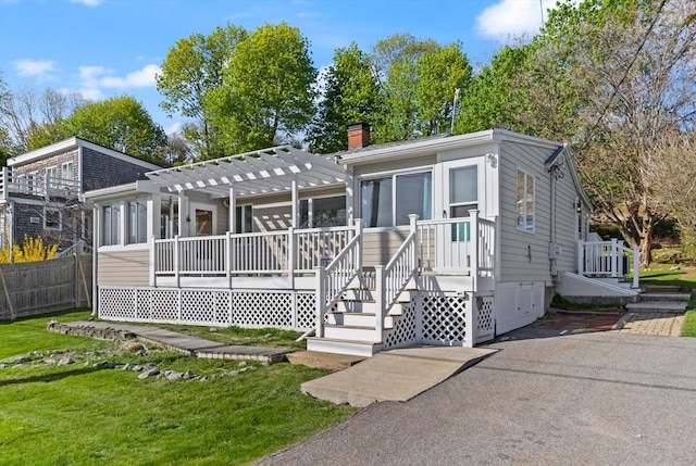 view of front of house with a chimney, fence, a pergola, crawl space, and a front lawn