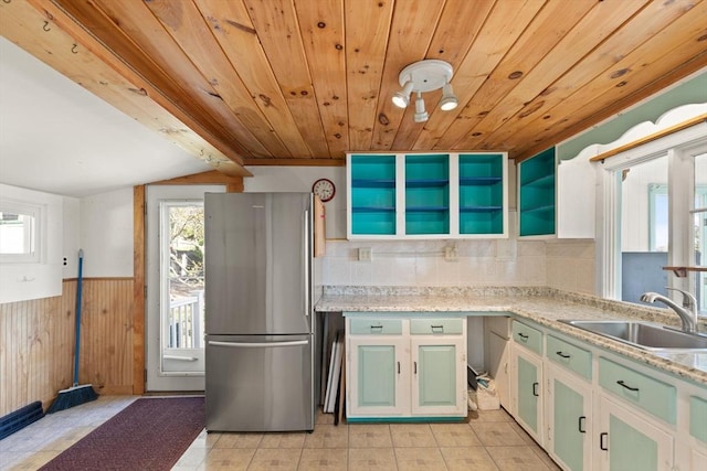 kitchen with wood ceiling, a sink, freestanding refrigerator, a wainscoted wall, and plenty of natural light