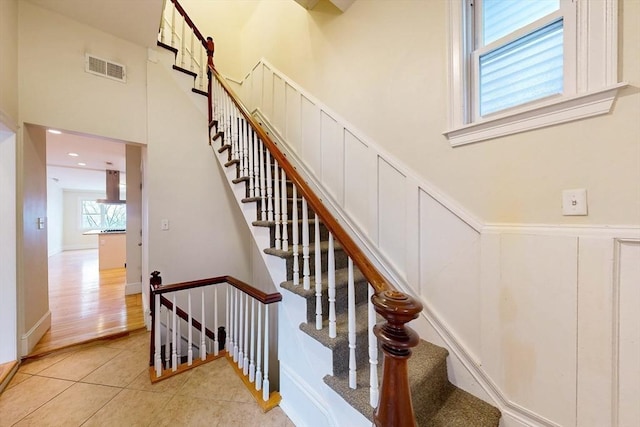 stairway featuring tile patterned floors, visible vents, and a towering ceiling