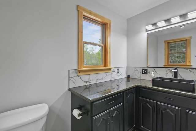 bathroom with healthy amount of natural light, tasteful backsplash, toilet, and vanity