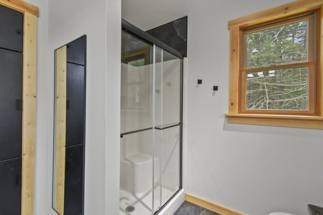 bathroom featuring a shower stall and baseboards