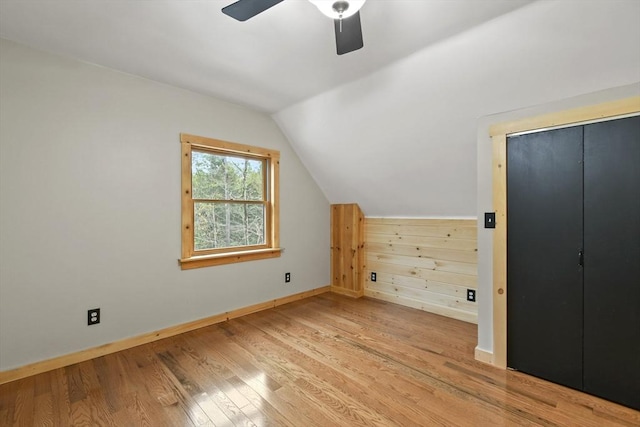 additional living space with vaulted ceiling, baseboards, light wood finished floors, and a ceiling fan