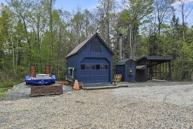 view of side of property with an outdoor structure, a garage, board and batten siding, and gravel driveway