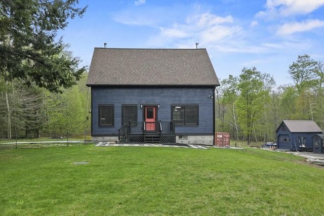 rear view of property with a lawn, roof with shingles, and an outbuilding
