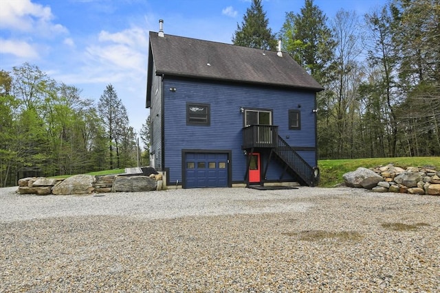 view of front of house with roof with shingles, stairway, an attached garage, and driveway