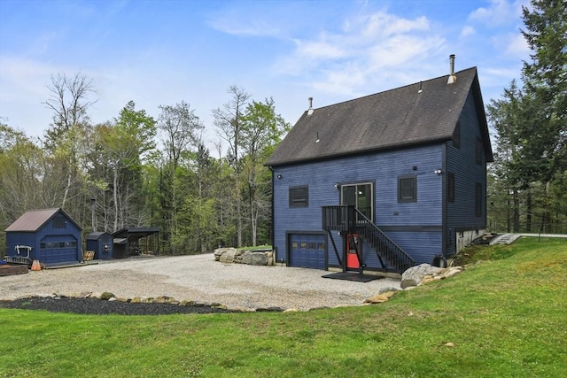 rear view of house featuring a yard, a shingled roof, driveway, a garage, and stairs