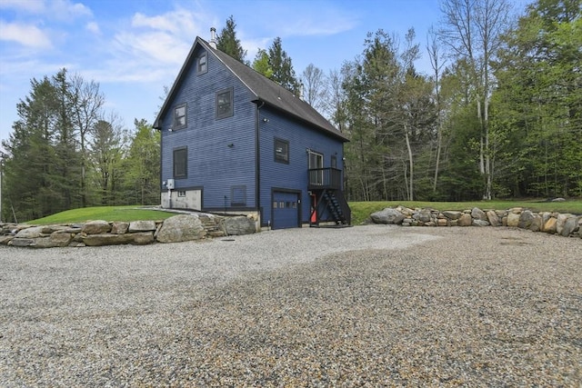 view of side of property with an attached garage, stairs, and driveway