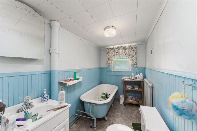 full bath featuring a wainscoted wall, vanity, a freestanding tub, radiator, and ornamental molding