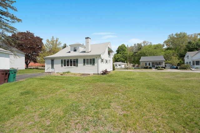 back of property featuring a chimney and a yard