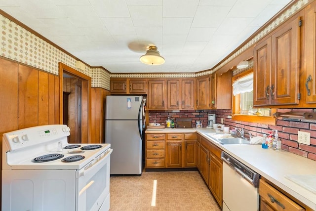 kitchen featuring white appliances, brown cabinetry, light countertops, ornamental molding, and a sink