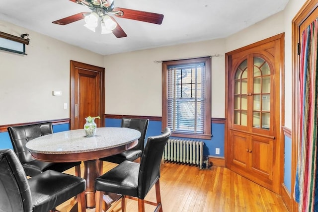 dining area featuring ceiling fan, light hardwood / wood-style flooring, and radiator heating unit