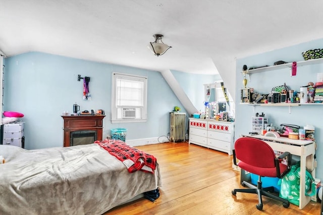 bedroom featuring hardwood / wood-style floors, radiator heating unit, lofted ceiling, and cooling unit