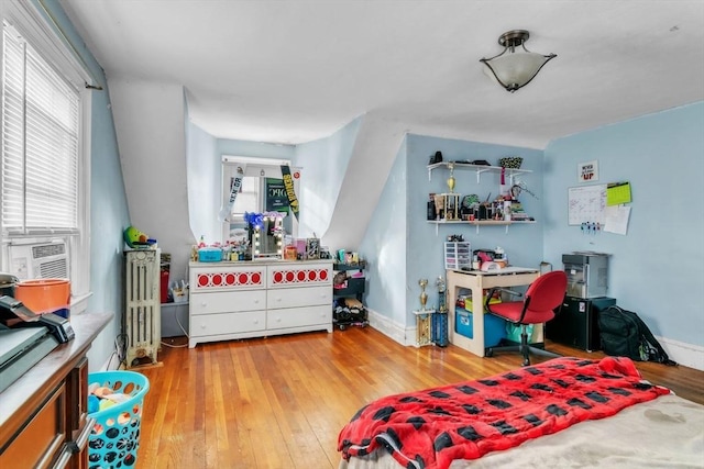 bedroom featuring cooling unit, radiator heating unit, and light wood-type flooring