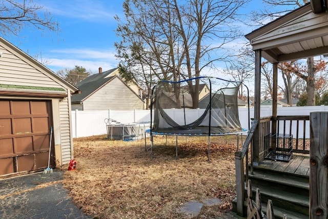 view of yard featuring a trampoline and a garage