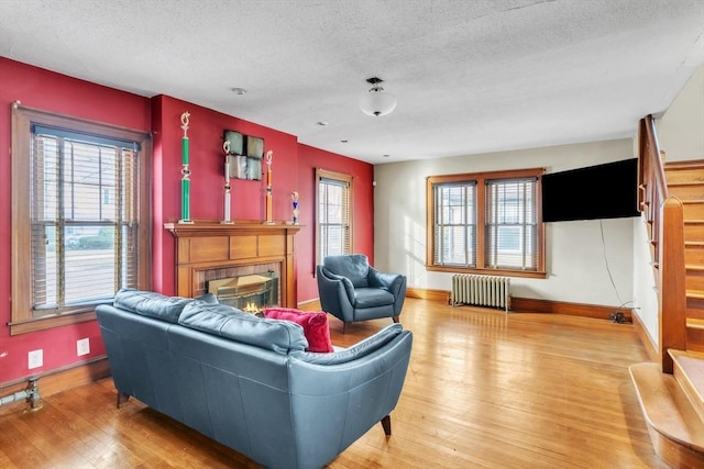 living room with a textured ceiling, a fireplace, wood-type flooring, and radiator heating unit